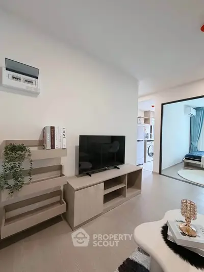 Modern living room with sleek TV stand and open view to kitchen and bedroom
