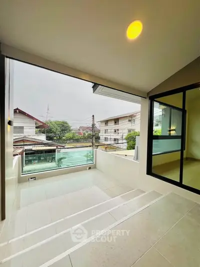 Modern balcony with glass railing offering a serene neighborhood view, perfect for relaxation and outdoor enjoyment.