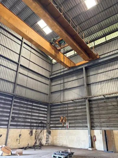 Spacious industrial warehouse with high ceilings and overhead crane system, ideal for manufacturing or storage.
