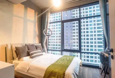 Modern bedroom with large windows offering stunning city views in a high-rise apartment.