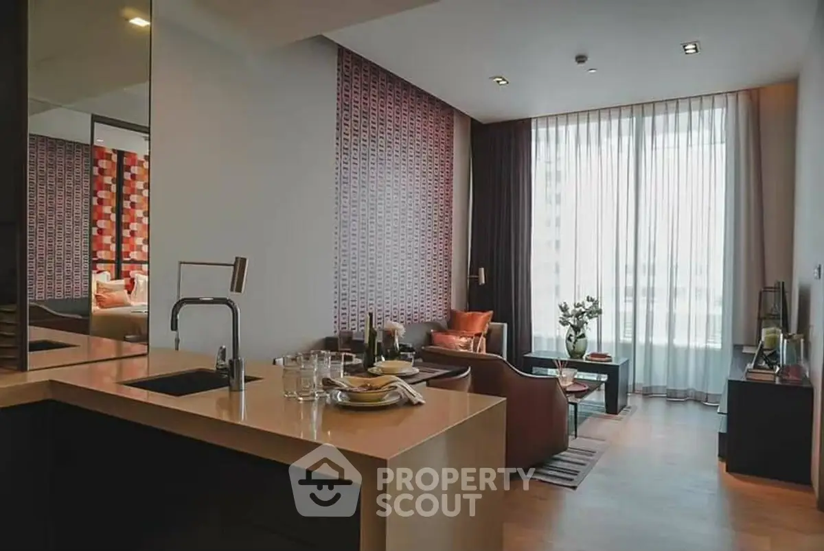 Modern open-plan living room with stylish decor and large window, featuring a cozy seating area and sleek kitchen counter.