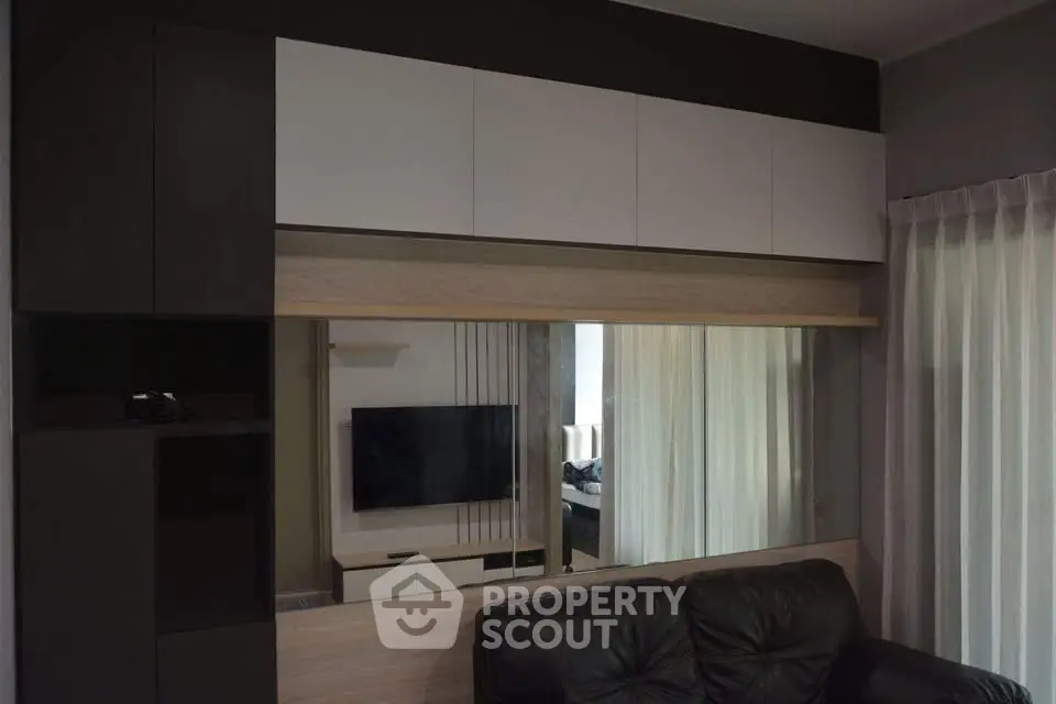 Modern living room with sleek cabinetry and wall-mounted TV, featuring a cozy leather sofa.