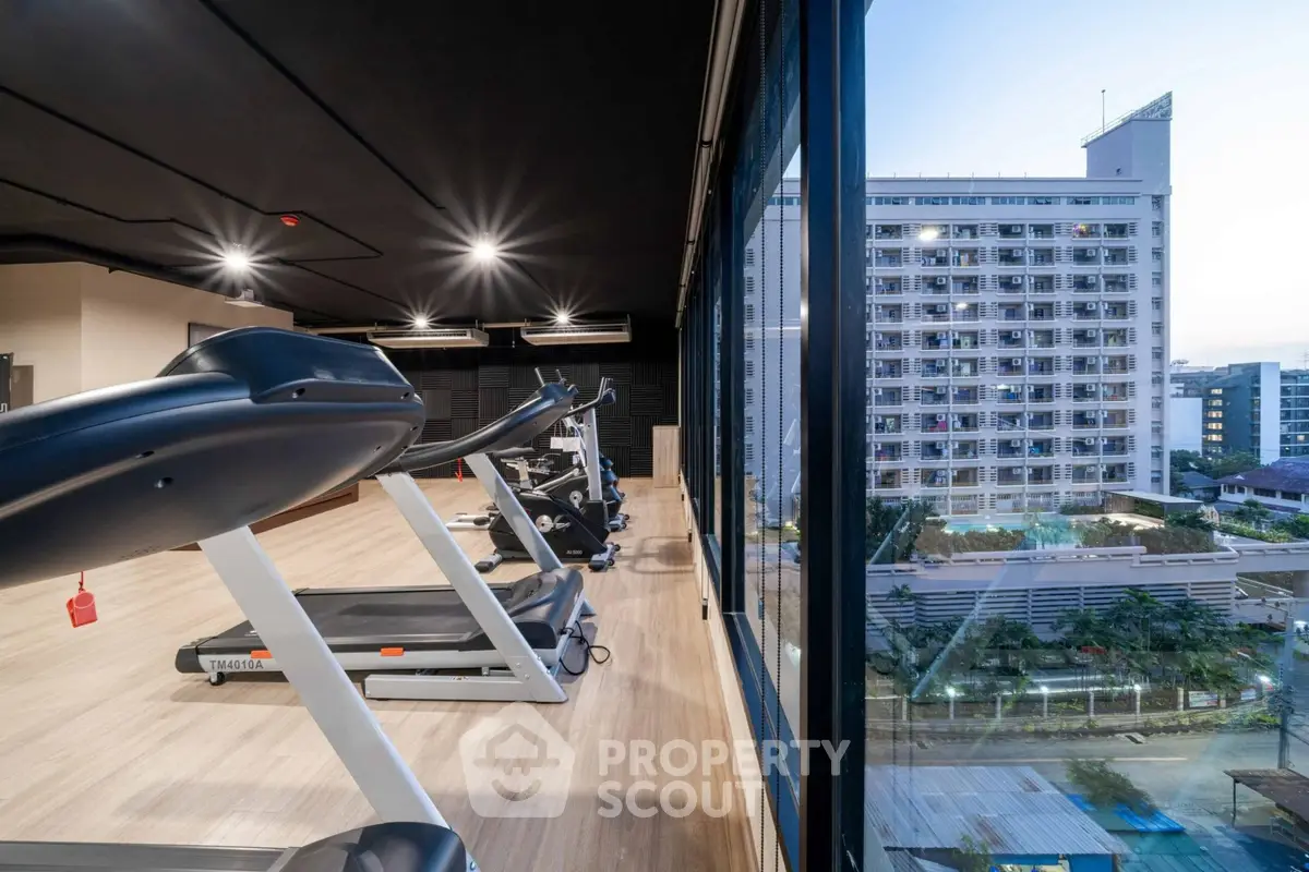 Modern gym with city view and state-of-the-art equipment in luxury building.