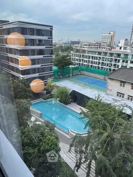 Stunning urban view with pool and tennis court from high-rise apartment.
