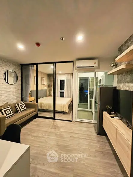 Modern living room with stylish decor and open view into cozy bedroom, featuring sleek furniture and ambient lighting.