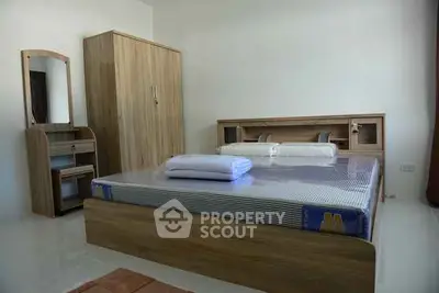 Spacious bedroom with modern wooden furniture and ample natural light.