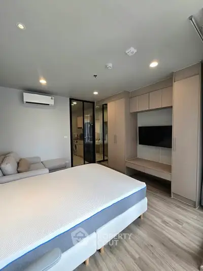 Modern bedroom with sleek design, featuring a comfortable bed, built-in wardrobe, and wall-mounted TV.