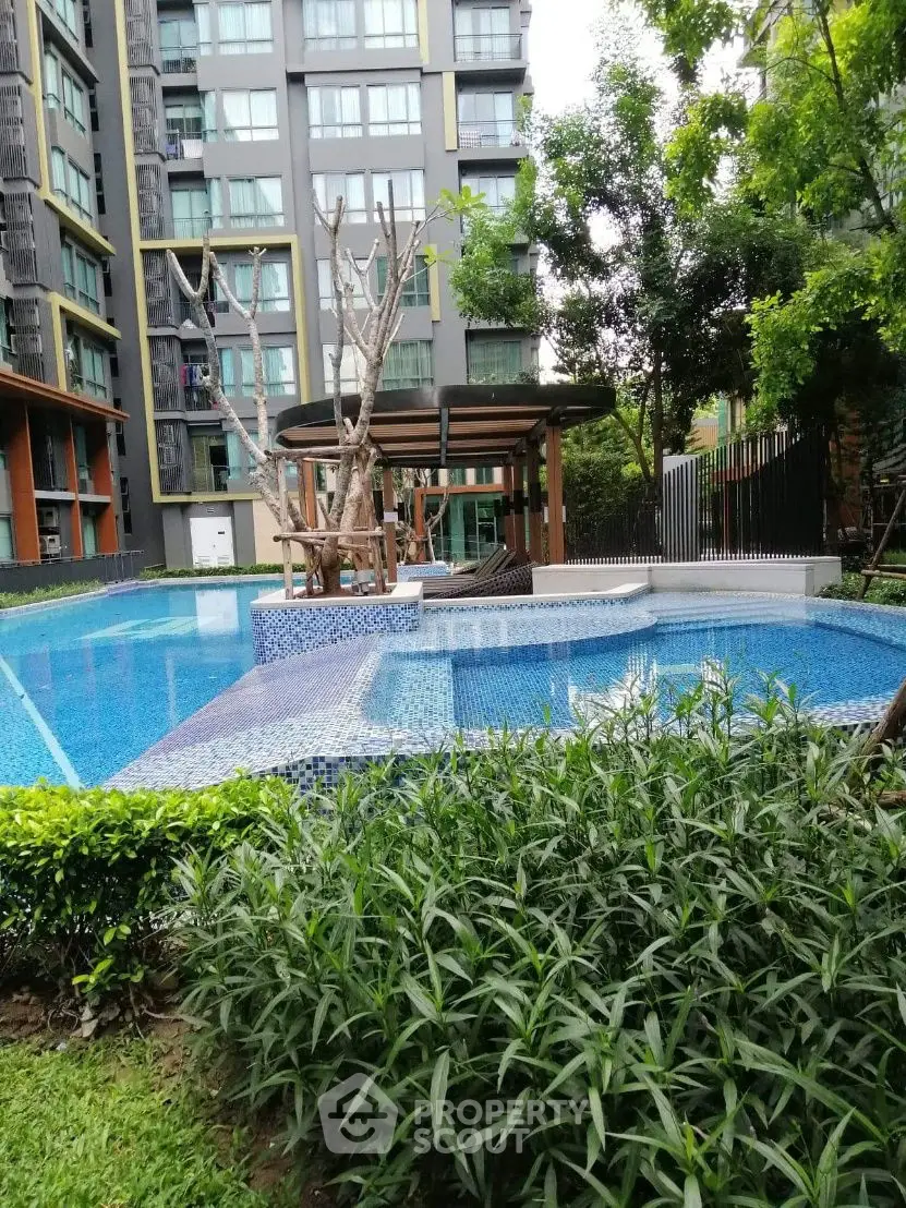 Luxurious apartment complex with modern pool and lush greenery