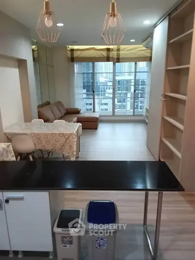 Modern living room with open layout and city view, featuring stylish lighting and cozy seating area.