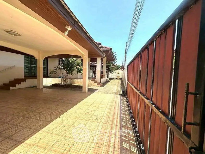 Spacious exterior view of a modern house with tiled patio and gated entrance.
