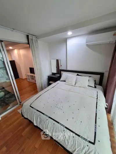 Cozy bedroom with wooden flooring and modern decor in a stylish apartment.