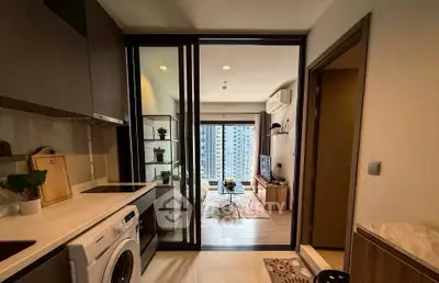 Modern apartment interior with open kitchen and cozy living room, featuring a washing machine and stylish decor.