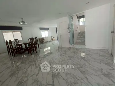 Spacious marble-floored living room with elegant dining set and staircase