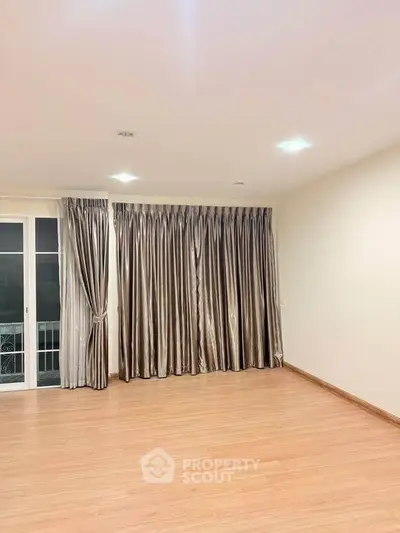 Spacious empty room with elegant curtains and wooden flooring, perfect for customization.