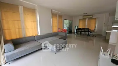 Spacious living room with modern gray sectional sofa and large windows, offering ample natural light and open space.
