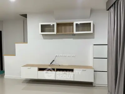 Modern minimalist living room with sleek white cabinetry and neutral tones.