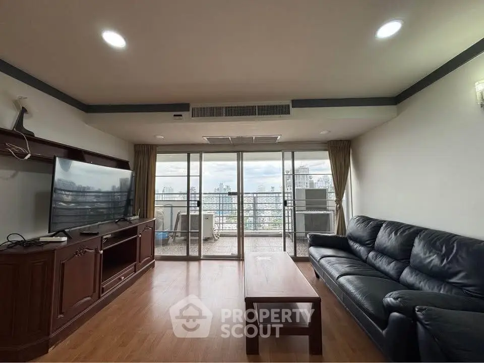 Spacious living room with balcony offering stunning city views, featuring modern furniture and ample natural light.