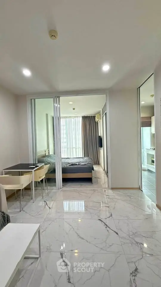 Modern apartment interior with marble flooring, dining area, and bedroom view.