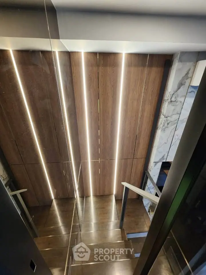 Modern staircase with sleek wooden panels and ambient lighting in luxury home