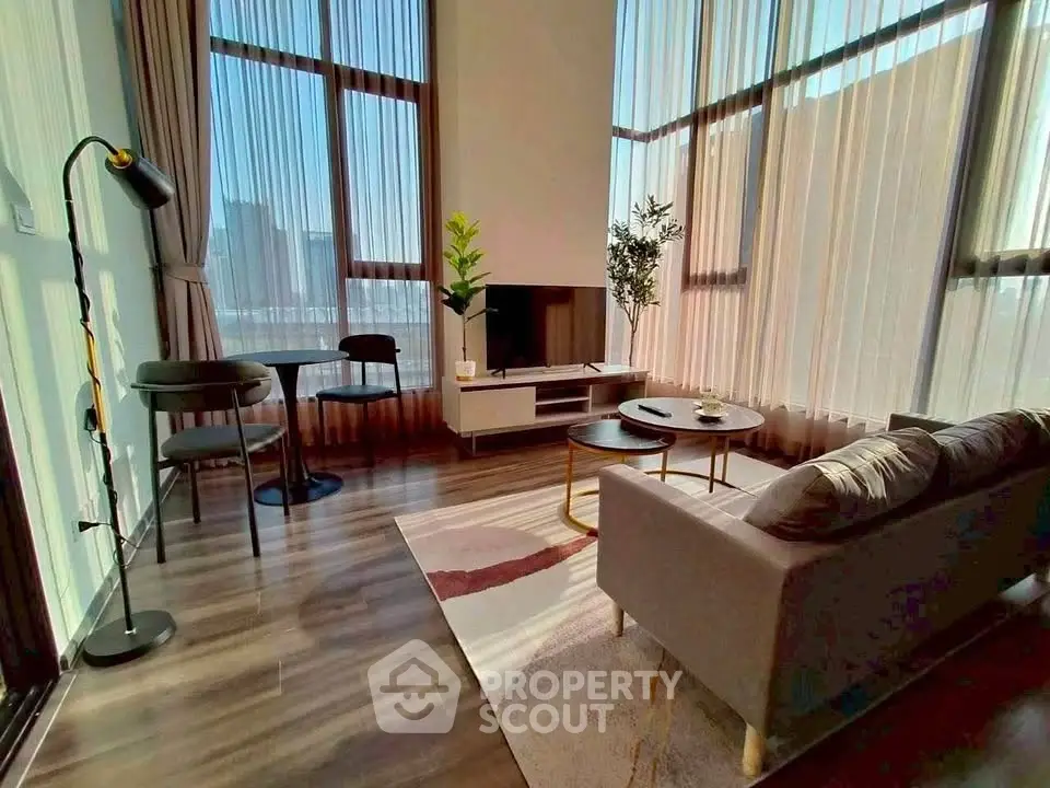 Spacious modern living room with high ceilings and large windows offering city views.