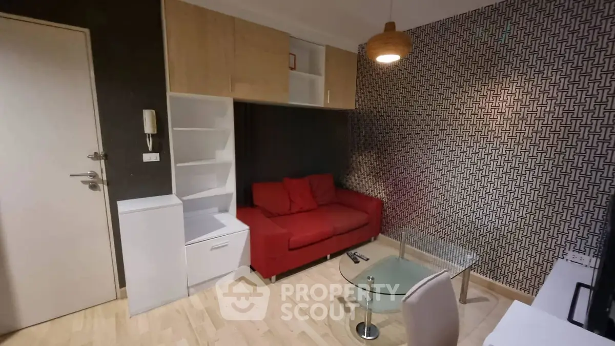 Modern living room with red sofa, stylish wallpaper, and sleek furniture in a cozy apartment.