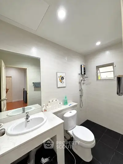 Modern bathroom with sleek fixtures and minimalist design, featuring a shower and vanity.