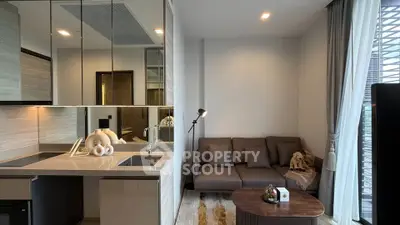 Modern living room with sleek kitchen and cozy seating area in a stylish apartment.