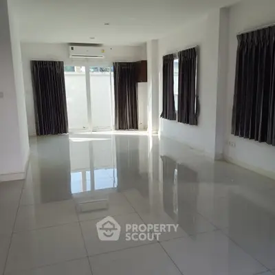 Spacious empty living room with glossy tiled floors and large windows.
