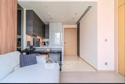 Modern open-layout kitchen with sleek cabinetry and cozy living area in a stylish apartment.