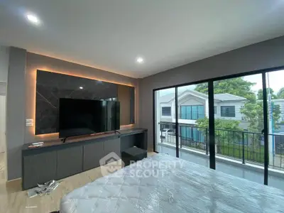 Modern bedroom with large TV and balcony view in a stylish home.