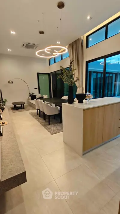 Modern open-plan living and dining area with stylish lighting and large windows.