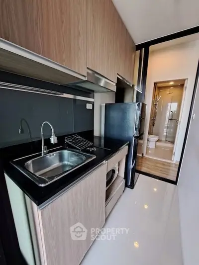 Modern compact kitchen with sleek cabinetry and integrated appliances in a stylish apartment.