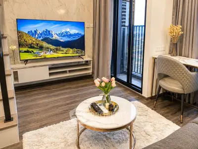 Modern living room with stylish decor, large TV, and balcony access, perfect for relaxation and entertainment.