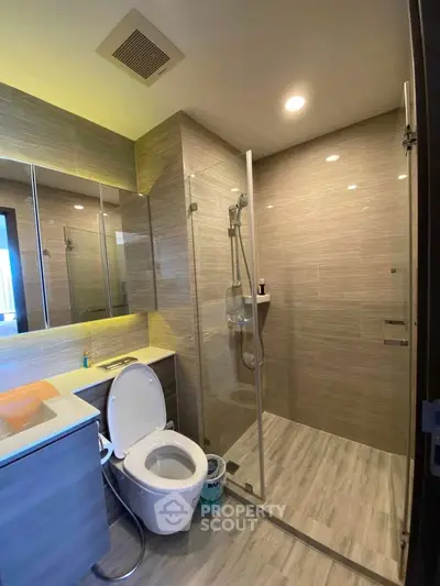 Modern bathroom with glass shower and sleek fixtures in contemporary apartment.