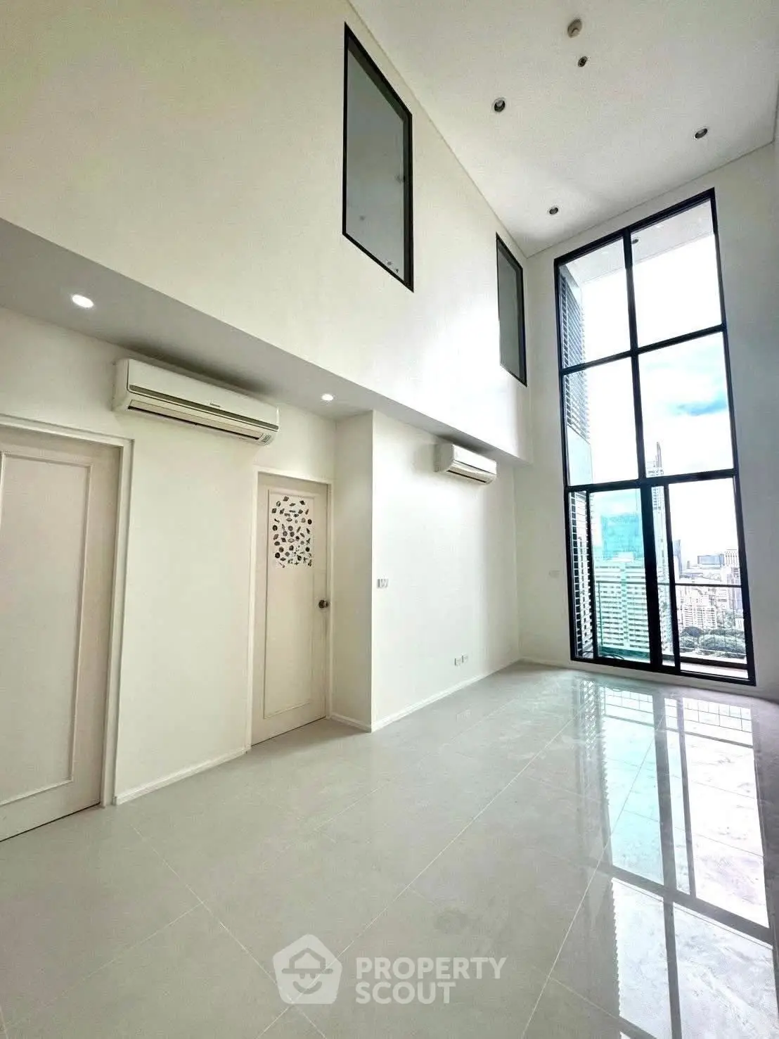 Spacious modern living room with high ceilings and large windows offering stunning city views.