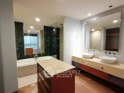 Luxurious bathroom with dual sinks, modern bathtub, and elegant wood cabinetry.