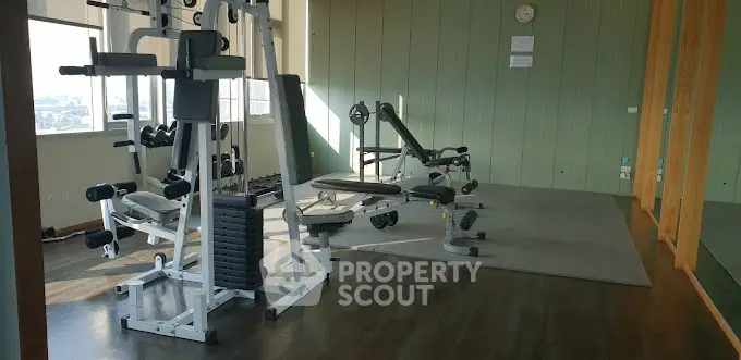 Spacious gym with modern equipment and large windows offering a city view.