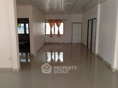 Spacious empty room with tiled flooring and large windows, perfect for customization.
