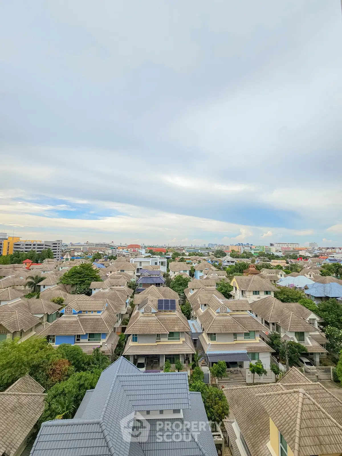 Aerial view of suburban neighborhood with uniform houses and lush greenery under a cloudy sky.