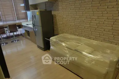 Modern kitchen with brick wall, sleek appliances, and wrapped furniture in stylish apartment.