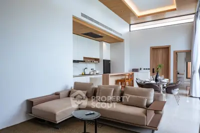 Luxurious modern living room with open kitchen and elegant dining area, featuring sleek furniture and high ceilings.
