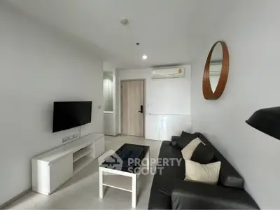 Modern living room with sleek black sofa, wall-mounted TV, and minimalist decor in a stylish apartment.