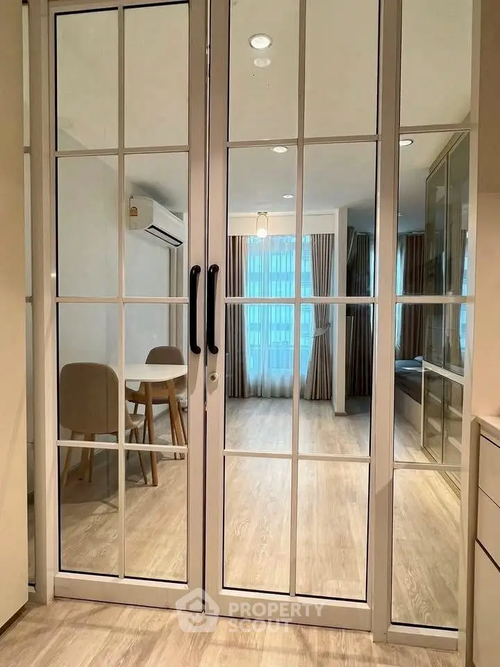 Modern interior with glass doors leading to a dining area, featuring wooden floors and elegant curtains.