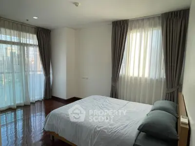 Spacious bedroom with large windows and elegant curtains in modern apartment