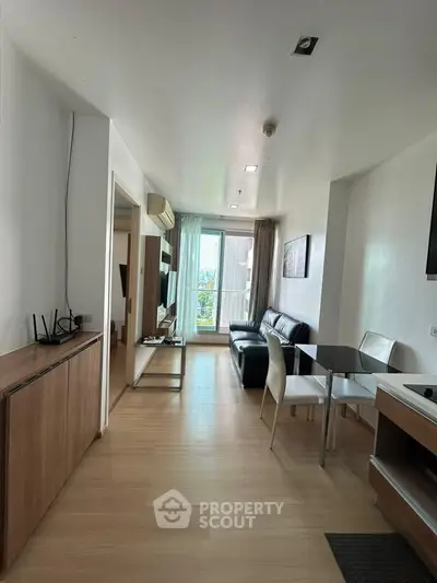 Modern living room with sleek furniture and natural light, featuring a compact dining area and balcony access.