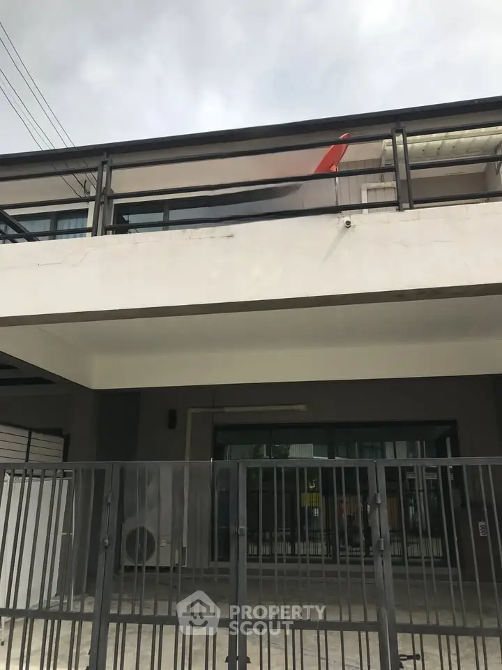Modern building exterior with sleek balcony and gated entrance