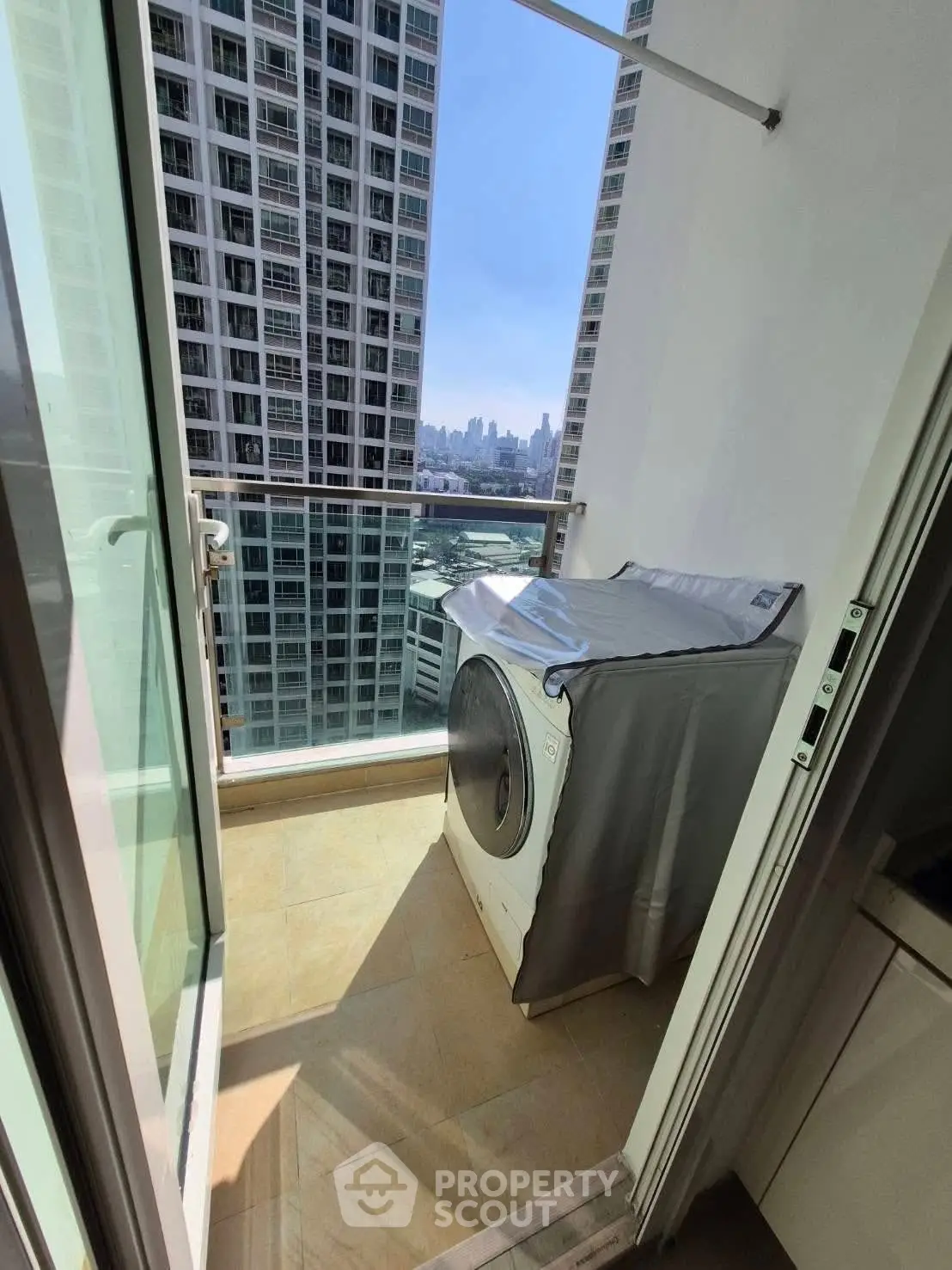 Modern balcony with washing machine and stunning city view in high-rise apartment.