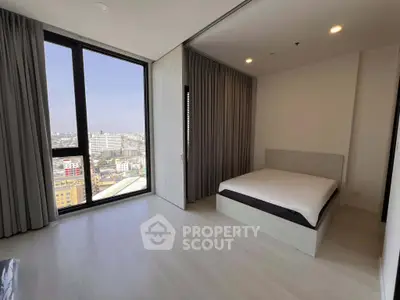 Spacious bedroom with large windows offering stunning city views in modern apartment.