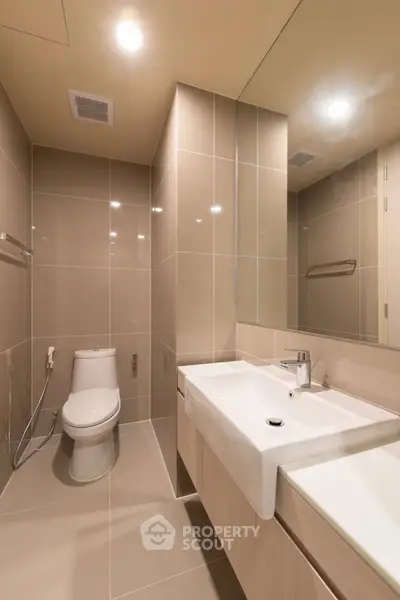 Modern bathroom with sleek fixtures and neutral tiles, featuring a spacious vanity and contemporary design.
