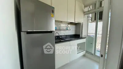 Modern kitchen with sleek cabinets and stainless steel fridge in a bright apartment.